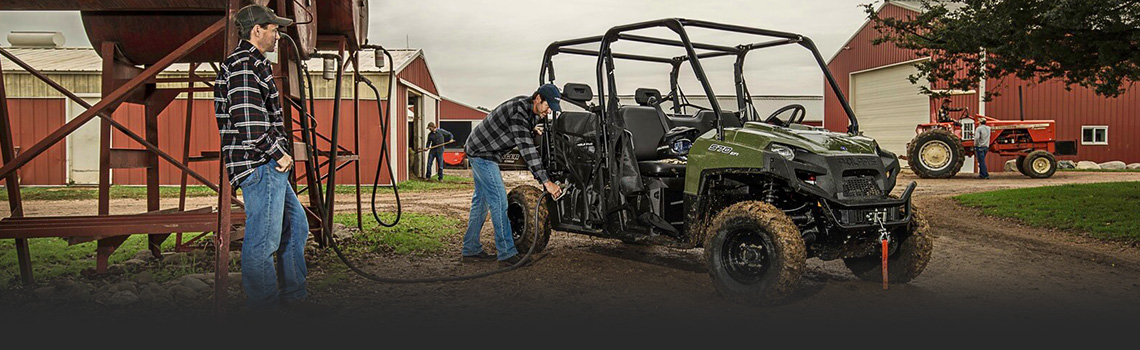 Two men next to a 2017 Polaris® Ranger Crew 570 6 on the farm fueling up their vehicle.
